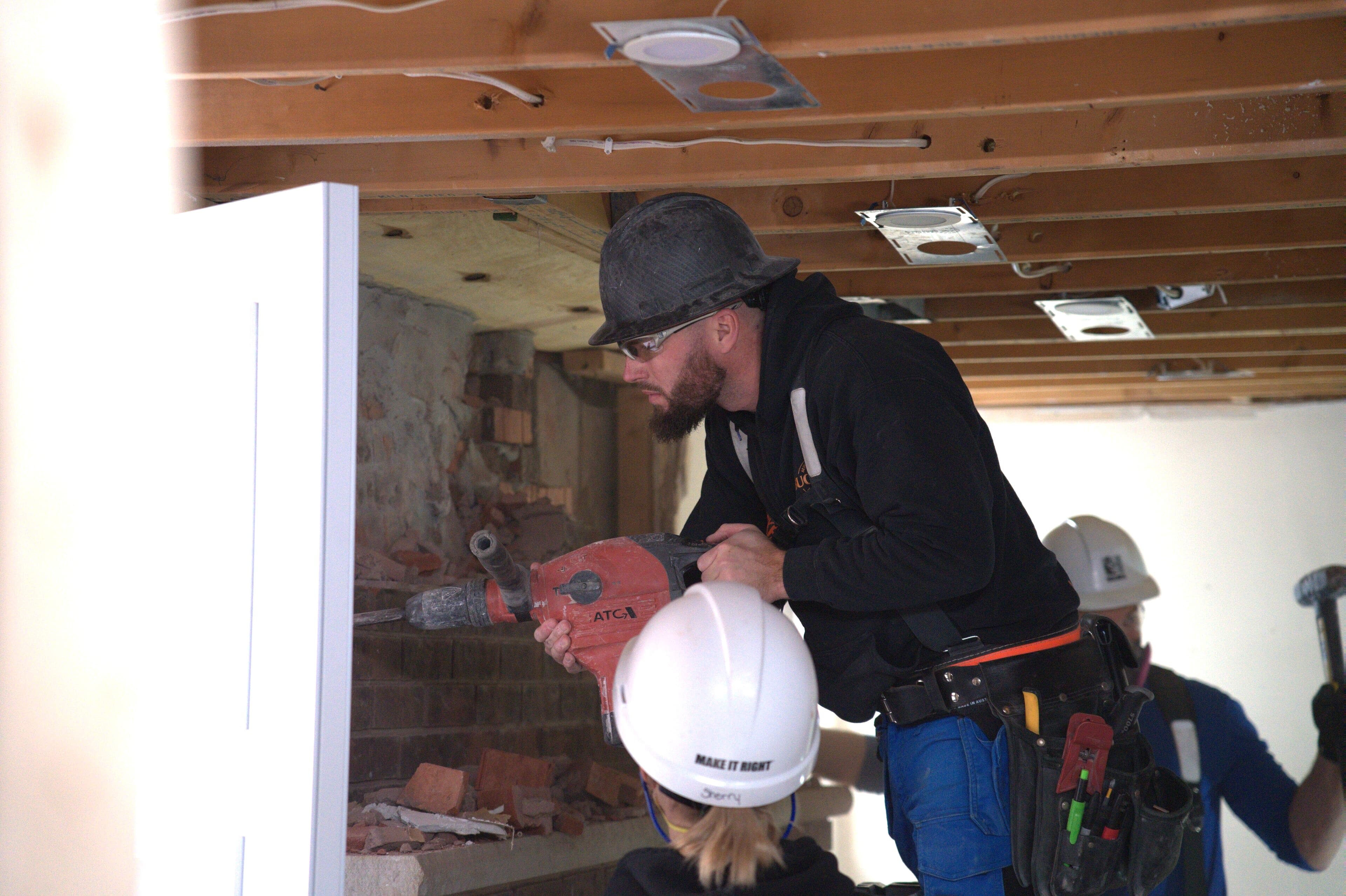 Blake Steed using power tool to perform demolition on exposed brick during renovation